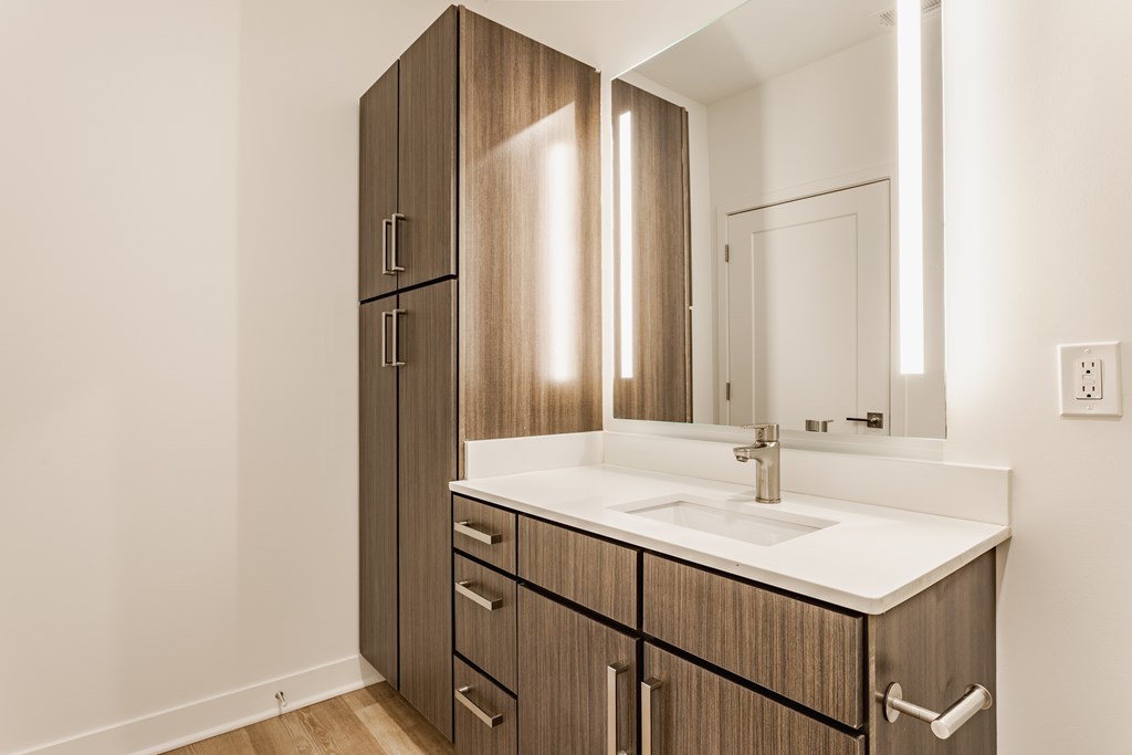 A bathroom with a sink, mirror, and wooden cabinets at Upper Vue Flats, Dublin