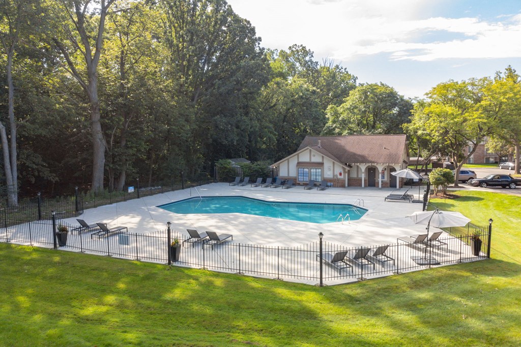 a pool with a fence around it and a house in the background at Cordoba Apartments, Farmington Hills, MI