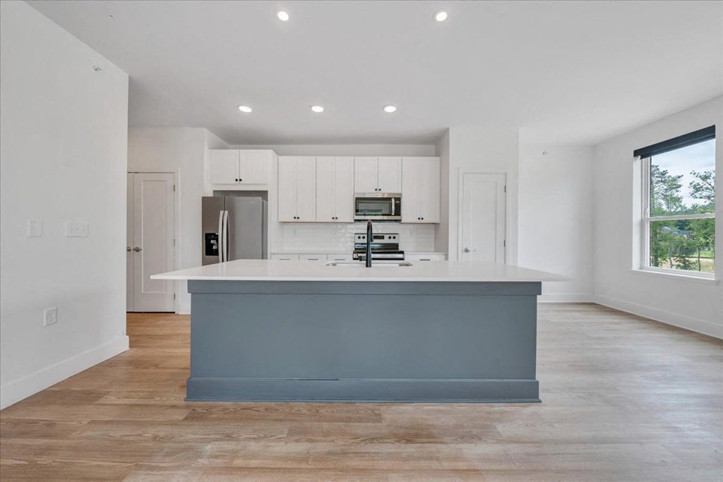 a kitchen with white cabinets and a blue island at Luxe 360 in Midlothian, Midlothian Virginia