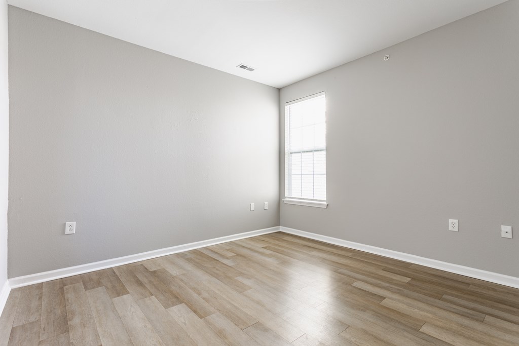 A room with wooden flooring and a window letting in light.