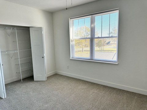 a bedroom with a large window and a closet  at Signature Pointe Apartment Homes, Athens, AL
