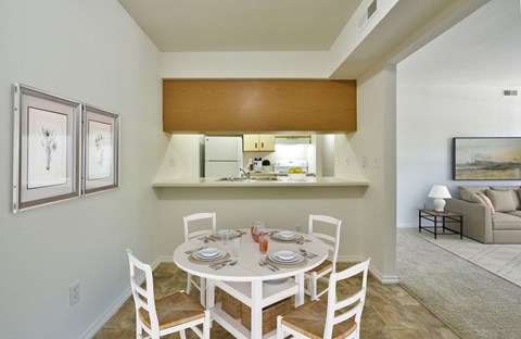 a dining area with a table and chairs and a kitchen in the background