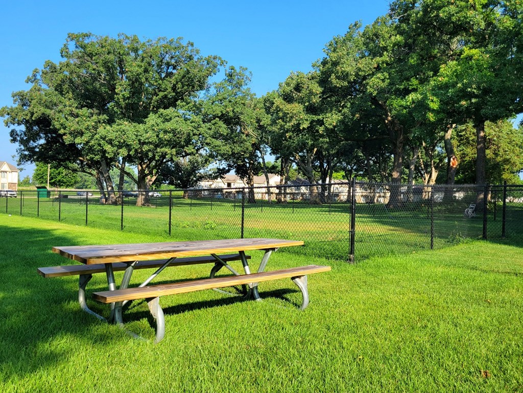 a picnic table in a grassy field with a chain link fence in the background at Beacon Hill and Great Oaks Apartments, Illinois