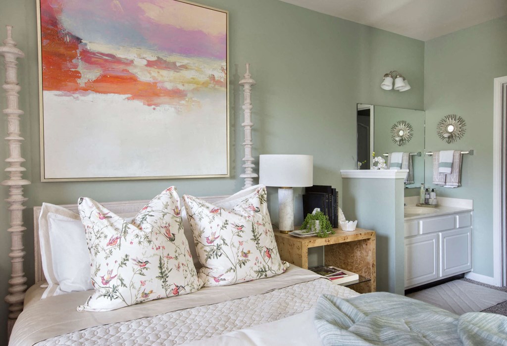 a bedroom with green walls and a white bed with floral pillows  at Enclave Apartments, Virginia