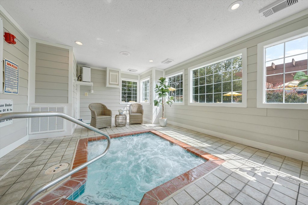 a hot tub in a room with a large window at Sunscape Apartments, Virginia