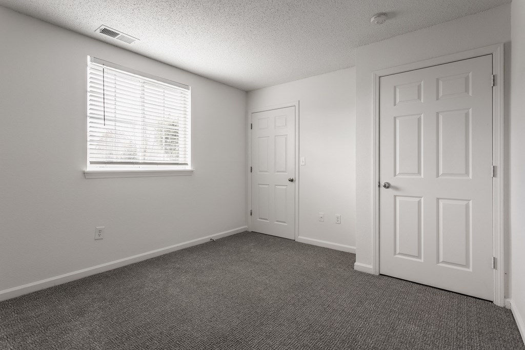 an empty living room with a white door and a window at Latitudes Apartments, Indianapolis, IN