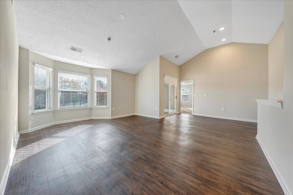 an empty living room with wood floors and windows