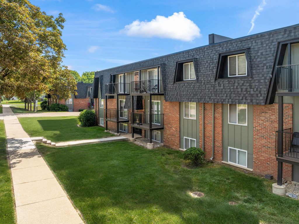 A building with a balcony and a green lawn in front