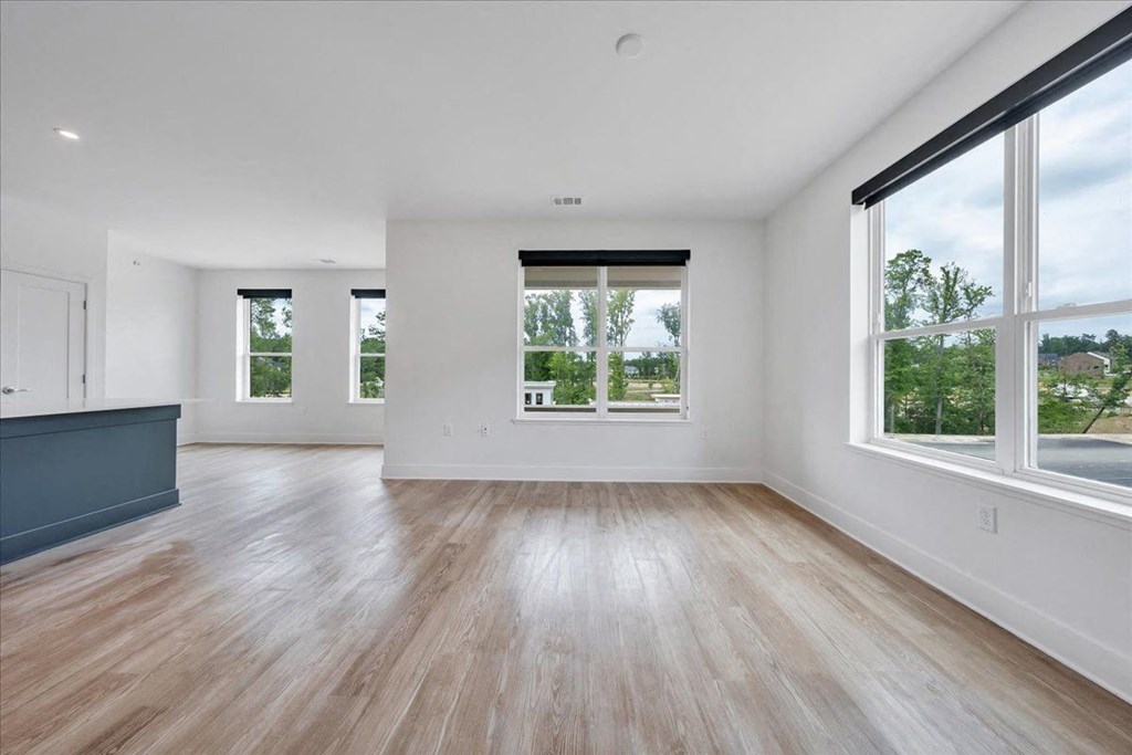 an empty living room with large windows and hardwood floors at Luxe 360 in Midlothian, Virginia, 23114