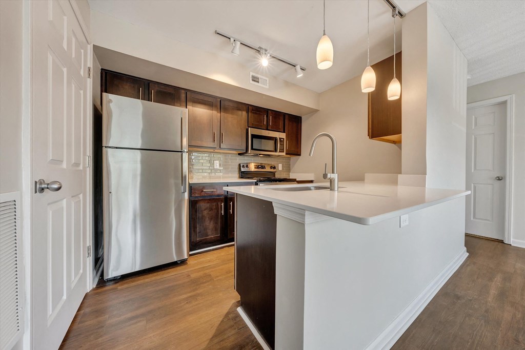 a kitchen with white countertops and dark wood cabinets at Sunscape Apartments, Virginia, 24018