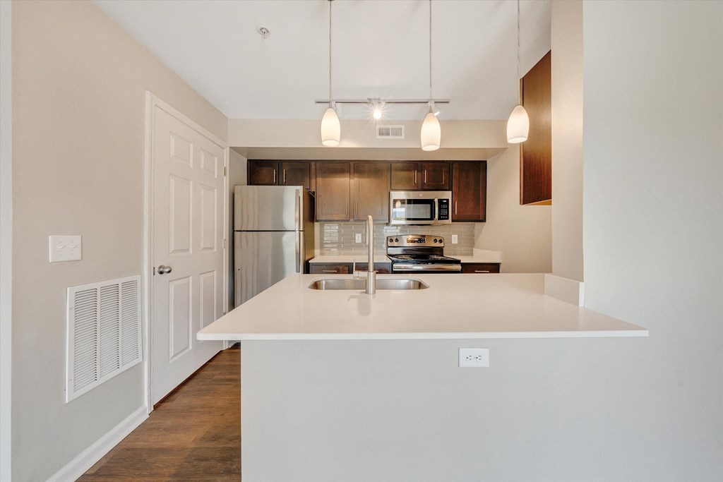 a kitchen with white countertops and wooden cabinets at Sunscape Apartments, Virginia, 24018