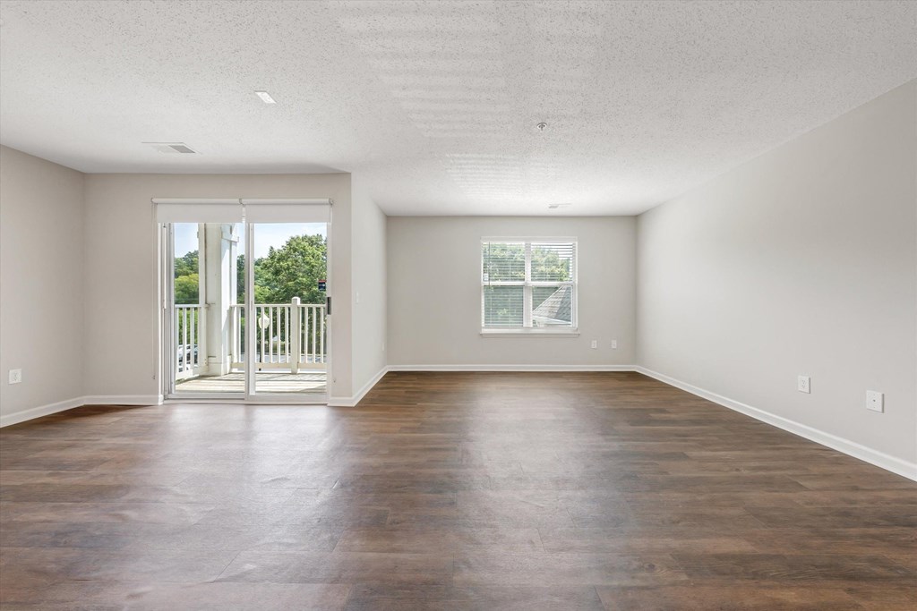 an empty living room with a sliding glass door and a balcony at Sunscape Apartments, Roanoke, 24018