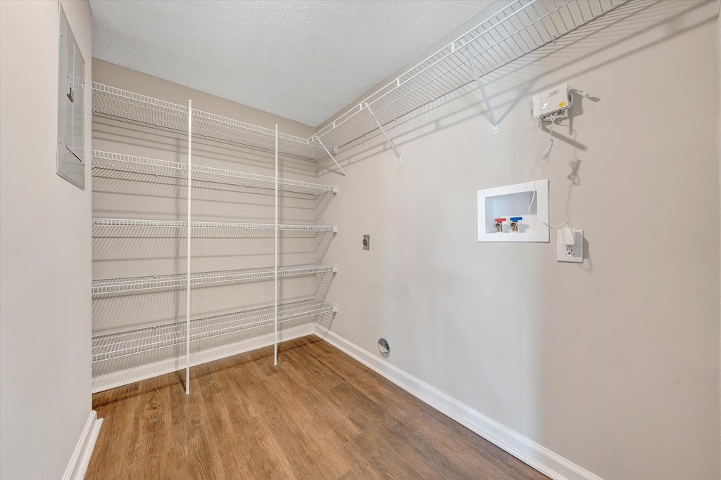 a room with a white wire shelving unit on the wall and a hardwood floor at Sunscape Apartments, Virginia, 24018