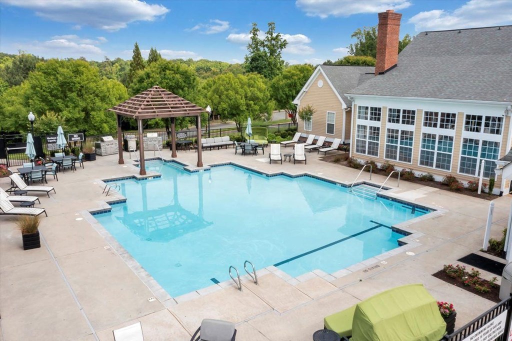 a swimming pool with lounge chairs and a house in the background  at Enclave Apartments, Midlothian