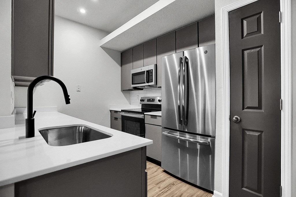 a kitchen with stainless steel appliances and a white counter top at Latitudes Apartments, Indianapolis