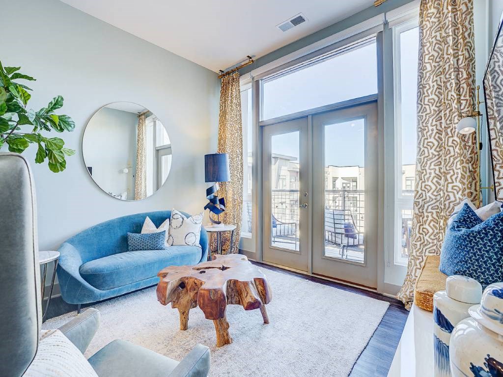 a living room with a blue couch and a large window  at Avant & Avant II, Carmel, IN, 46032