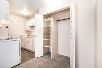 a kitchen with white cabinets and a large closet with shelving