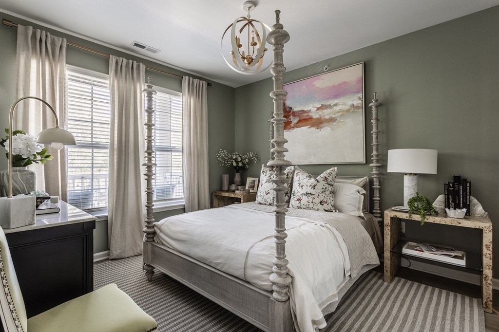 a bedroom with a white bed and a painting on the wall at Alexandria of Carmel Apartments, Carmel, IN, 46032