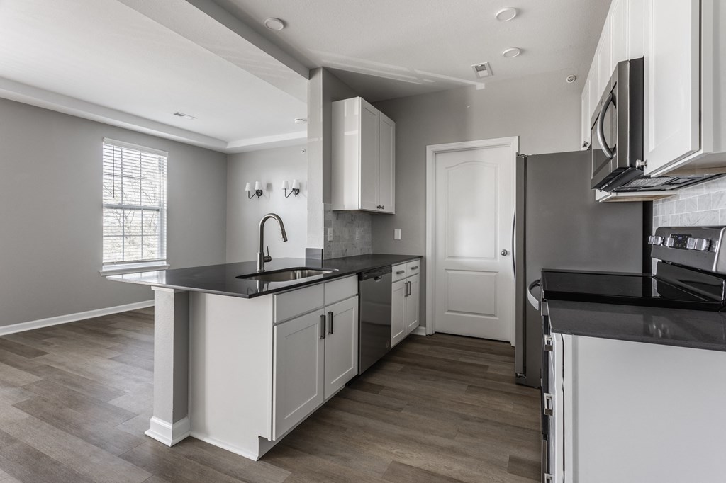an empty kitchen with white cabinets and black counter tops  at Alexandria of Carmel Apartments, Carmel, IN, 46032