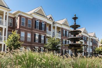 a large brick building with a fountain in front of it at Alexandria of Carmel Apartments, Carmel, Indiana
