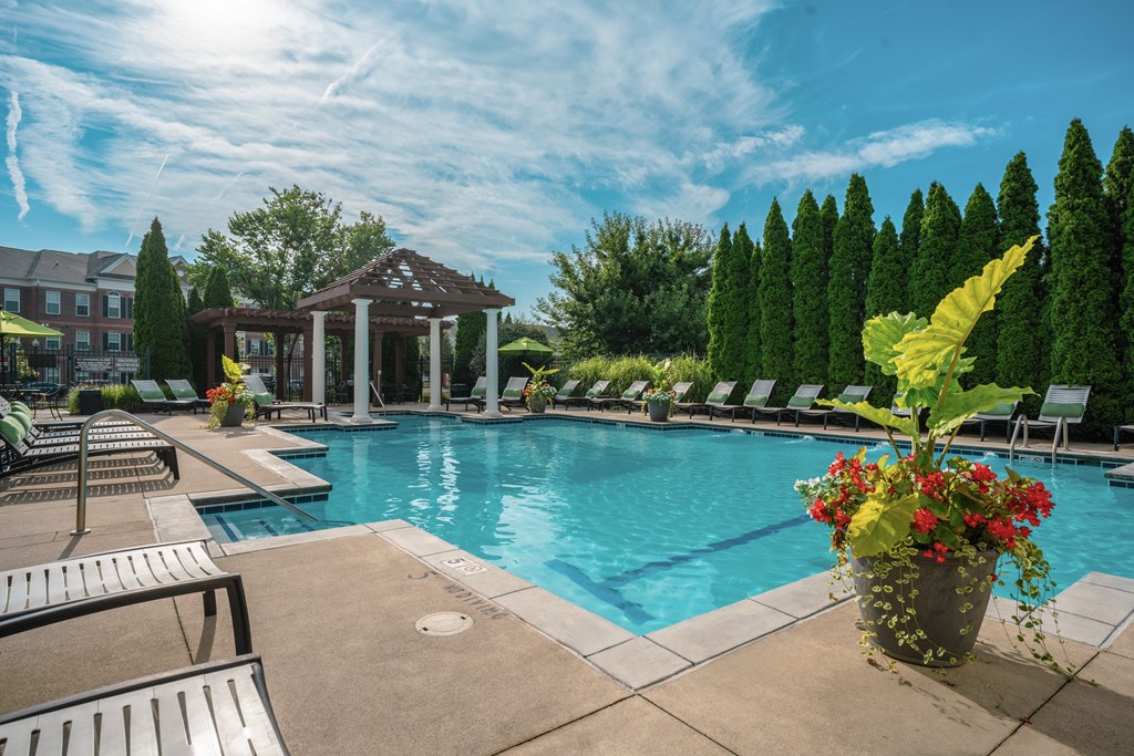 A pool area with a gazebo and lounge chairs.