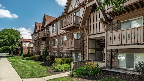 Apartment building with brown and beige exterior and a green lawn in front