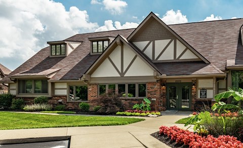 A house with a brown roof and white walls with a green lawn in front