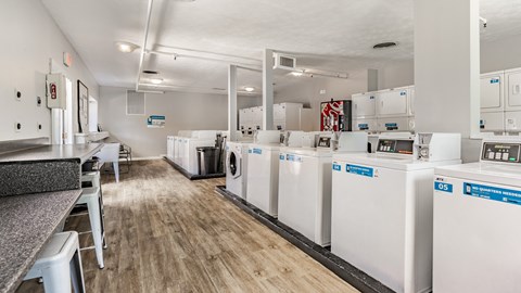 A laundry room with washers and dryers lined up