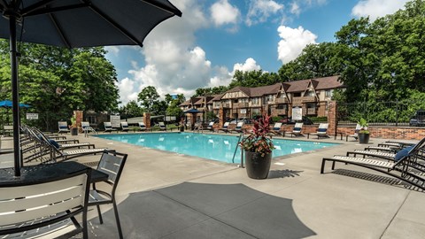 A pool area with a sun umbrella and benches