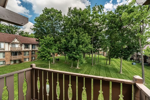 A balcony overlooks a grassy area with trees