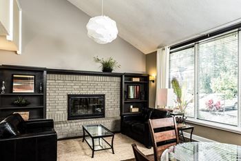 A living room with a fireplace and a glass table at Autumn Woods Apartments, Miamisburg