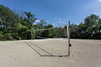 A volleyball net stands on a sandy court with trees in the background at Autumn Woods Apartments, Ohio