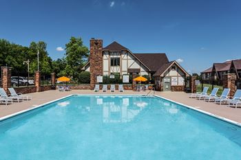 A large swimming pool in front of a house with lounge chairs around it at Autumn Woods Apartments, Miamisburg, Ohio
