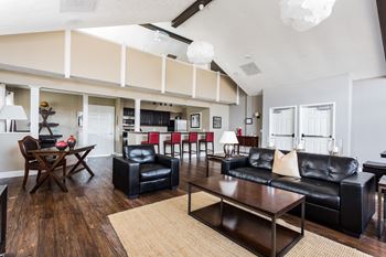 A living room with black leather furniture and a wooden floor at Autumn Woods Apartments, Ohio