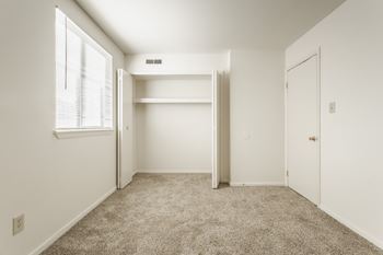 A white bedroom with a window and a carpeted floor. at Autumn Woods Apartments, Miamisburg, OH, 45342