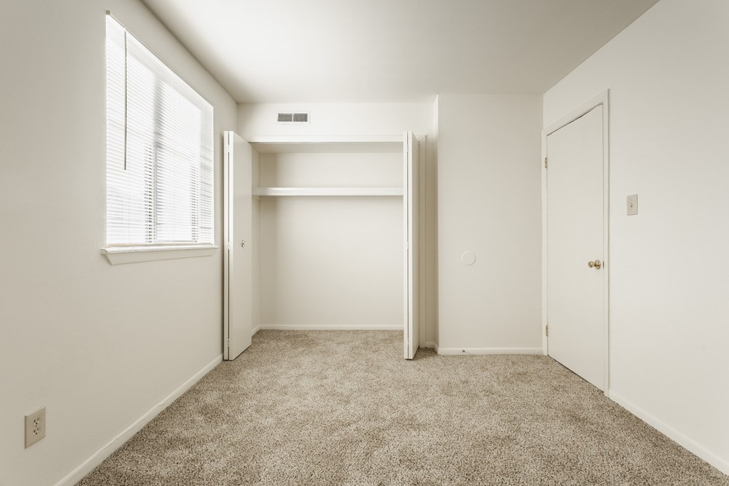 A white bedroom with a window and a carpeted floor. A white bedroom with a window and a carpeted floor at Autumn Woods Apartments, Ohio, 45342