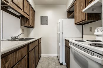 A kitchen with white appliances and wooden cabinets at Autumn Woods Apartments, Miamisburg