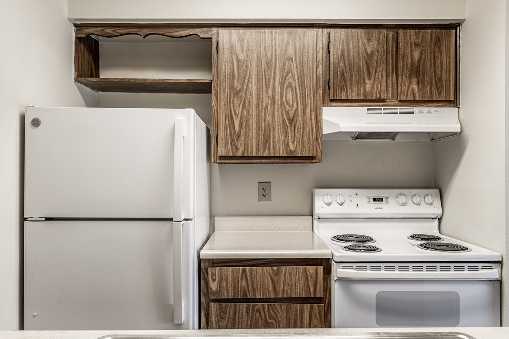 A white refrigerator and stove in a kitchen with wooden cabinets. A white refrigerator and stove in a kitchen with wooden cabinets at Autumn Woods Apartments, Miamisburg, OH