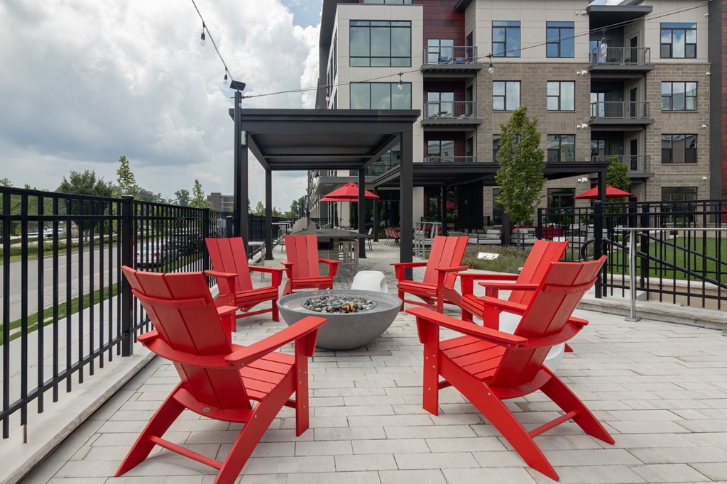 a group of red chairs sitting around a fire pit on a patio at Avant Apartments in Carmel, IN
