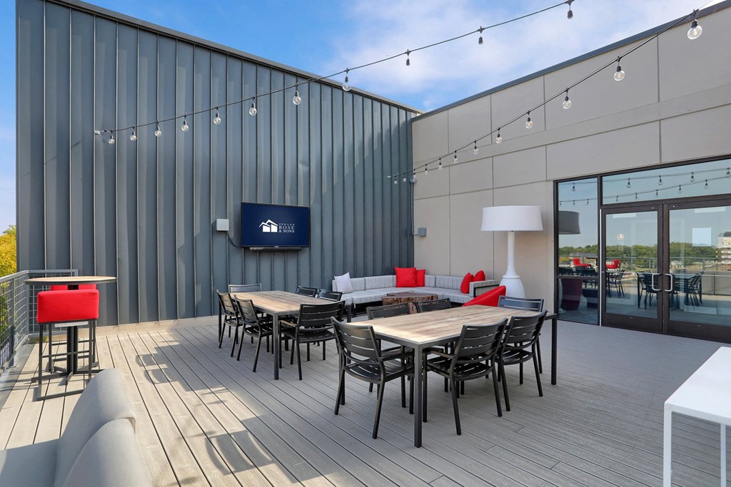 a rooftop patio area with tables and chairs and a tv in Carmel, IN