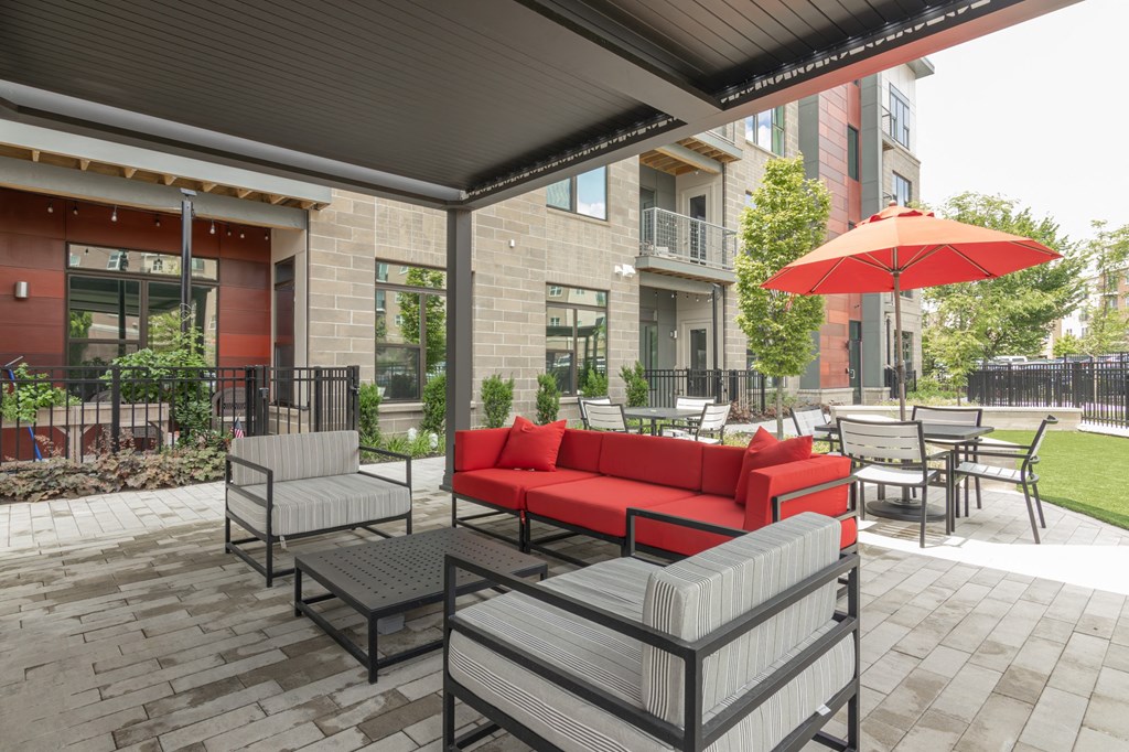 a patio with a red couch and tables with umbrellas in Carmel, IN, 46032