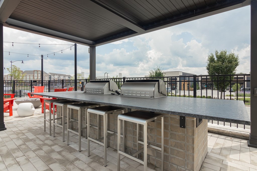 Grilling stations with chairs on a patio at Avant Apartments in Carmel, IN, 46032