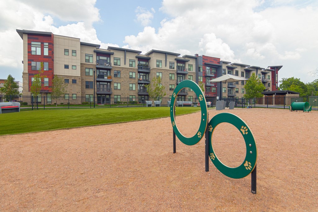 a leash-free pet park with agility equipment in front of an apartment building in Carmel, Indiana