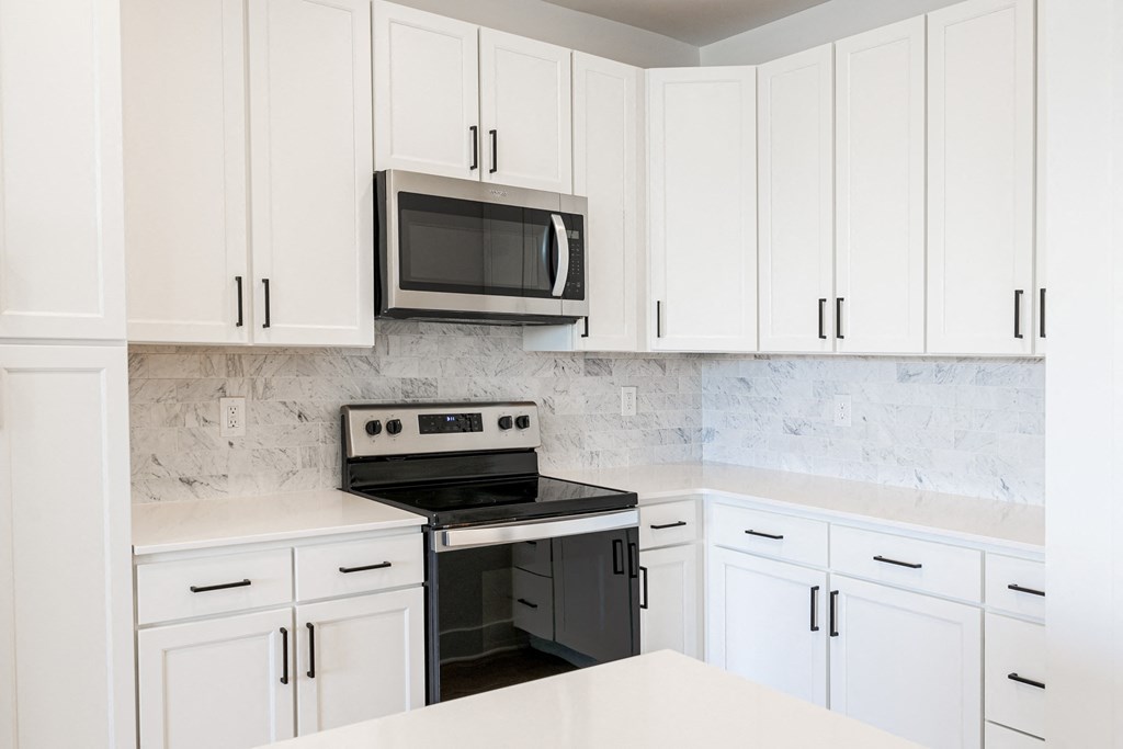 a kitchen with white cabinets and a black stove and microwave at Avant & Avant II, Carmel, IN, 46032