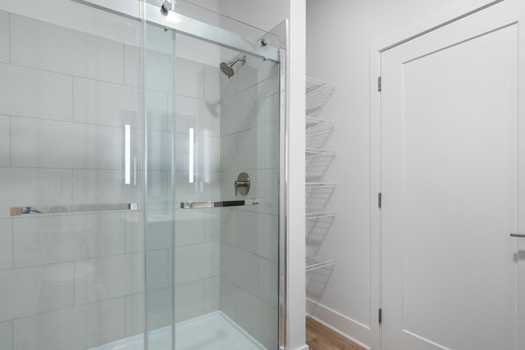 a shower with a glass door in a white bathroom at Avant Apartments in Carmel, IN, 46032