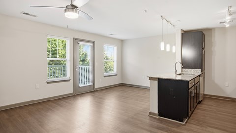 A kitchen area with a black fridge and a ceiling fan.