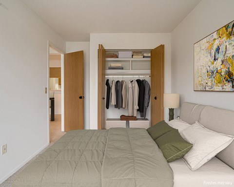 a bedroom with a bed and a closet with clothes in it