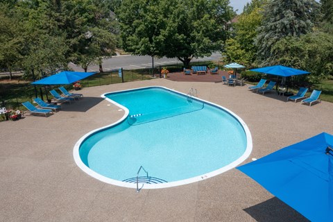 Outdoor swimming pool with sun loungers and blue umbrellas at Bristol Square and Golden Gate Apartments, Wixom, Michigan