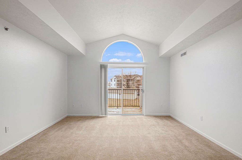 living room with a cathedral ceiling and a door to a balcony  at Black Sand Apartment Homes, Lincoln, 68504