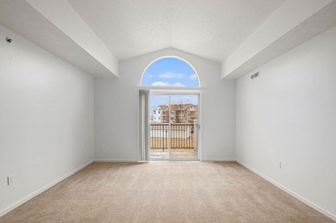 living room with a cathedral ceiling and a door to a balcony  at Black Sand Apartment Homes, Lincoln, 68504